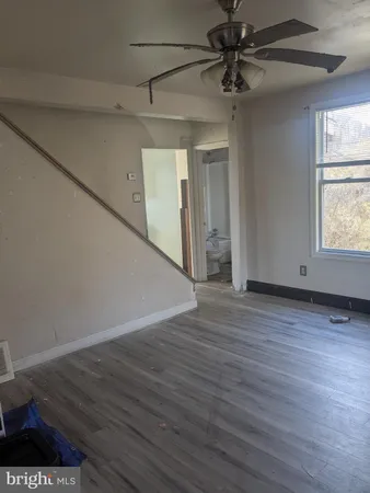a view of a livingroom with wooden floor a ceiling fan and windows