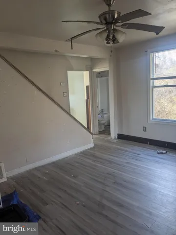 a view of a livingroom with wooden floor a ceiling fan and windows
