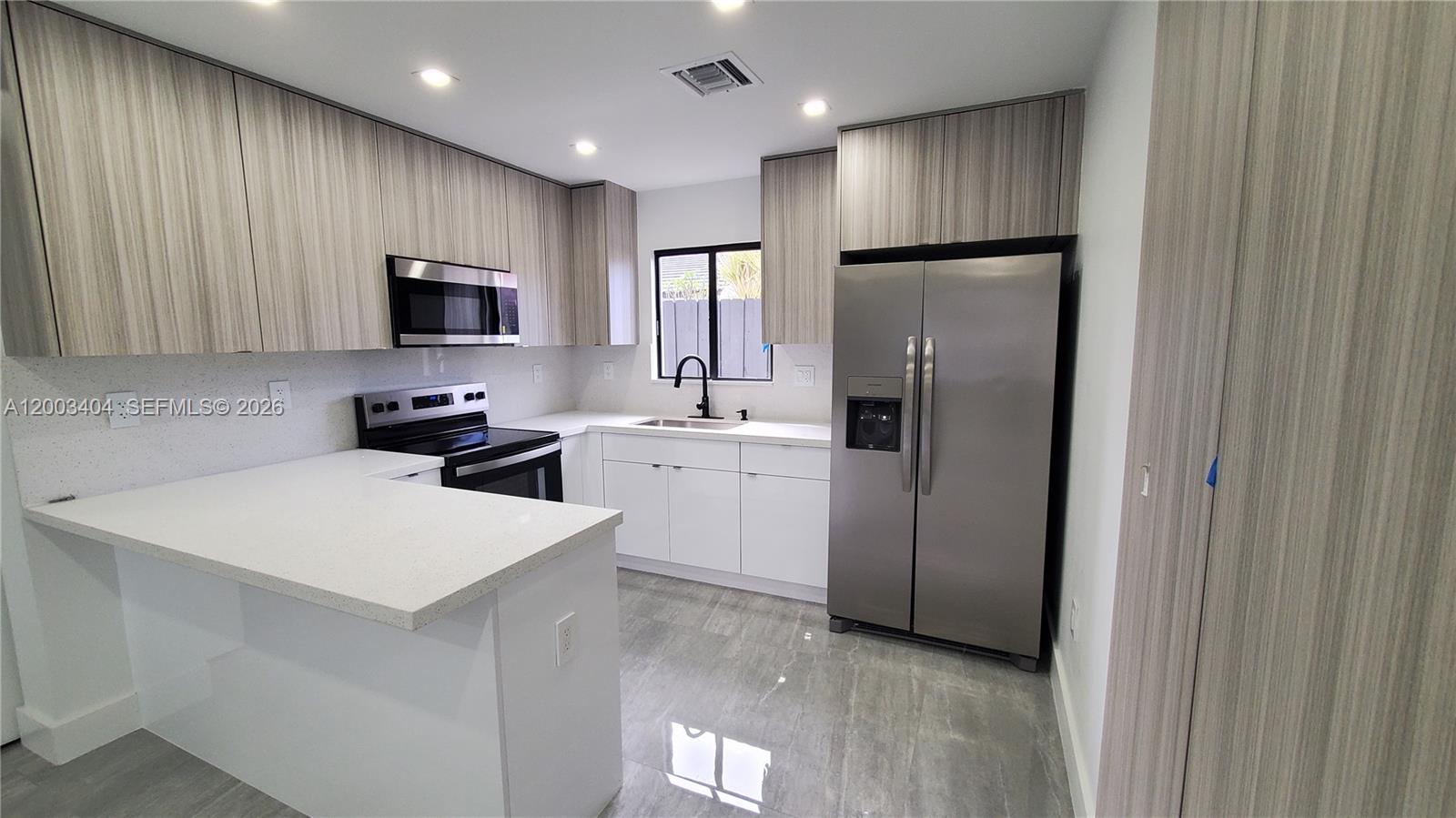 40 Southwest 34th Avenue, Unit C Miami, FL 33135 - Photo 3 of 24 a kitchen with kitchen island a refrigerator sink and microwave