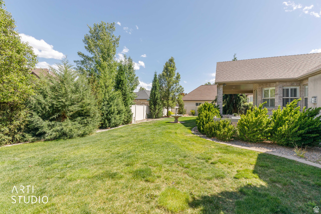 2327 Bluff Ridge Drive Syracuse, UT 84075 - Photo 53 of 66 Expansive backyard featuring a manicured lawn, established landscaping, and a covered patio