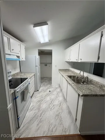 a kitchen with granite countertop a sink stove and refrigerator
