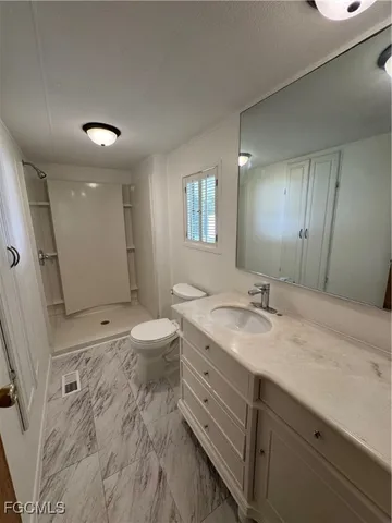 a bathroom with a granite countertop sink a toilet and a mirror