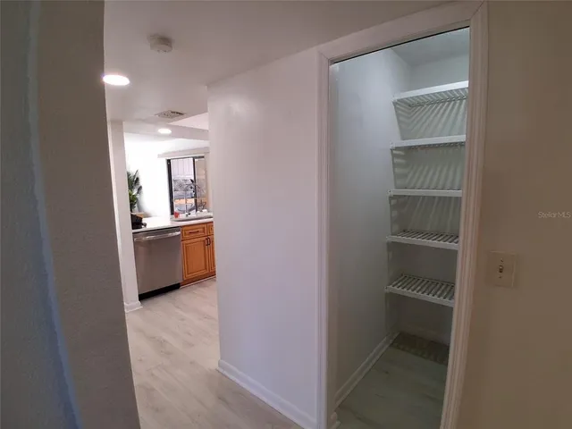 a view of a hallway with wooden floor and a bathroom