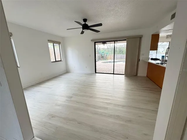 a view of empty room with wooden floor and fan