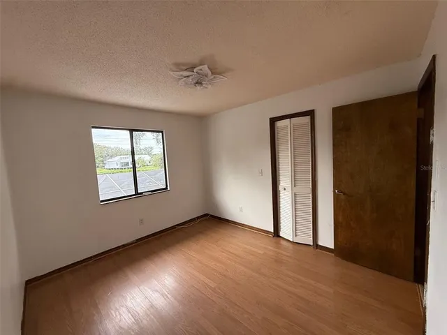 a view of empty room with wooden floor and fan