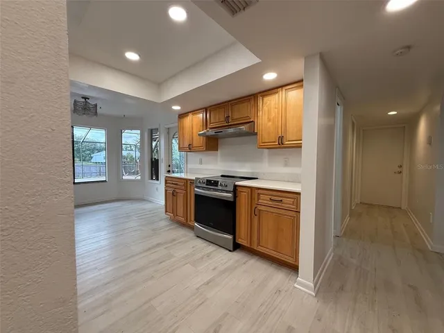 a large kitchen with stainless steel appliances granite countertop a large counter top and a wooden floors