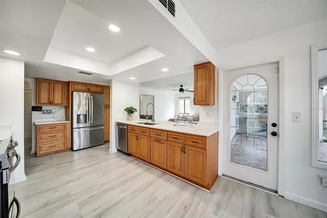 an empty room with wooden floor chandelier fan and windows