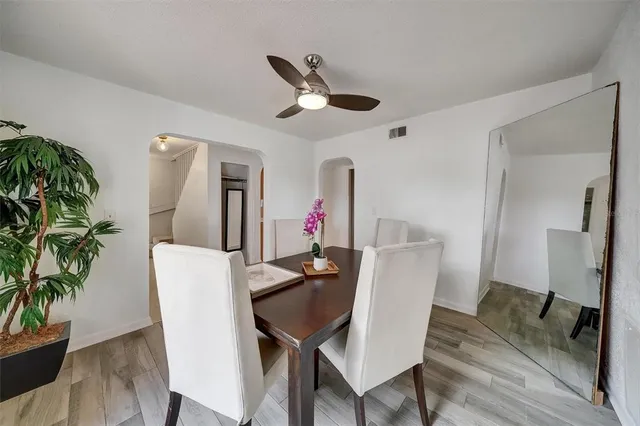 an empty room with wooden floor chandelier fan and windows