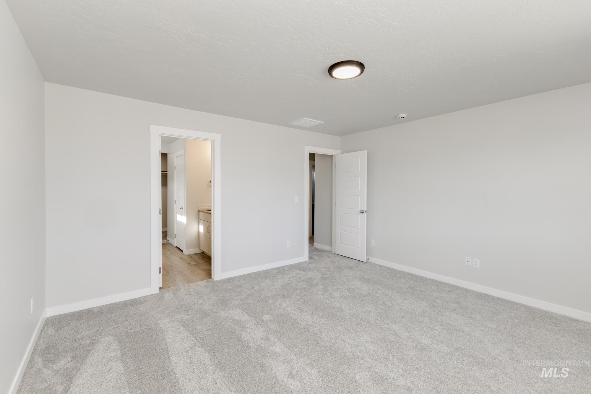 12853 Decatur Street Nampa, ID 83651 - Photo 22 of 24 Spacious room featuring plush gray carpeting, neutral wall finishes, white trim, and a modern flush-mount ceiling light