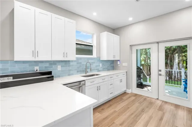 a kitchen with stainless steel appliances granite countertop a stove a sink and white cabinets
