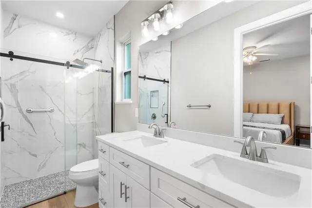 a bathroom with a double vanity sink toilet mirror and shower