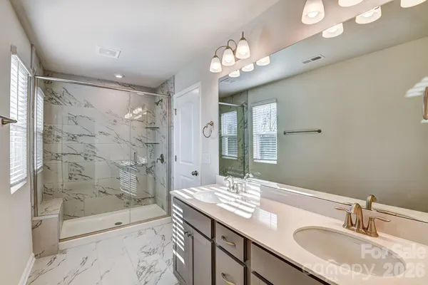 a bathroom with a granite countertop sink a toilet a mirror and shower