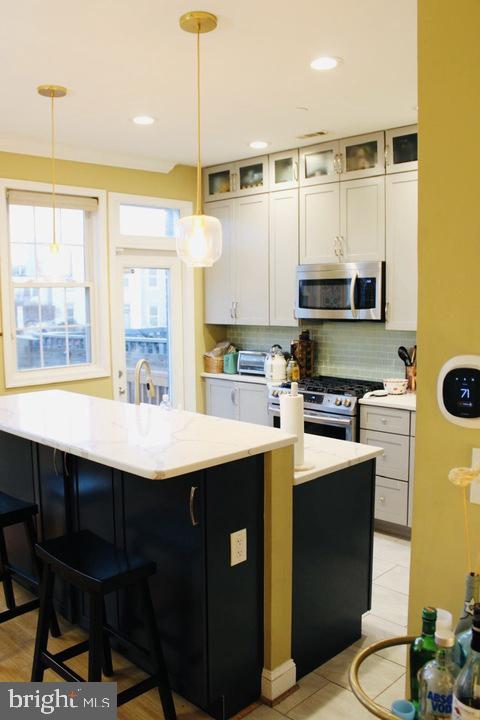 1011 8th Street Northeast Washington, DC 20002 - Photo 19 of 34 a kitchen with stainless steel appliances a sink a stove a refrigerator a center island with wooden floor and cabinets