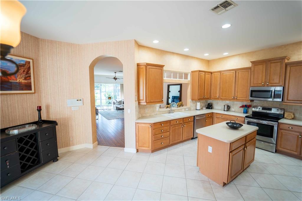 5886 Paradise Circle Naples, FL 34110 - Photo 4 of 19 Kitchen with light wood-type flooring, a center island, sink, stainless steel appliances, and ceiling fan