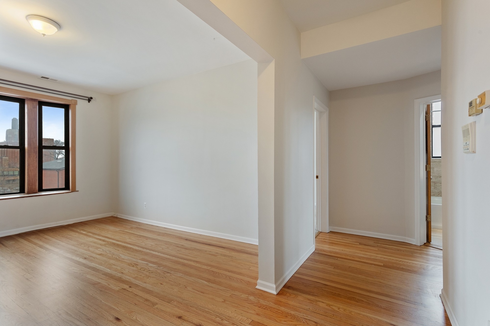 1409 East 62nd Street, Unit 3 Chicago, IL 60637 - Photo 2 of 10 a view of an empty room with wooden floor and a window
