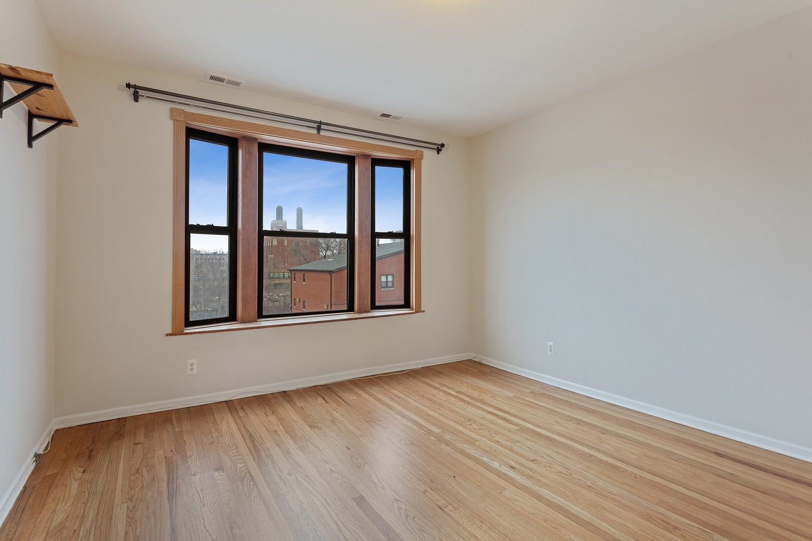 1409 East 62nd Street, Unit 3 Chicago, IL 60637 - Photo 4 of 10 a view of an empty room with wooden floor and a window