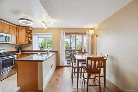 a kitchen with stainless steel appliances granite countertop a stove a refrigerator a kitchen island and chairs in it
