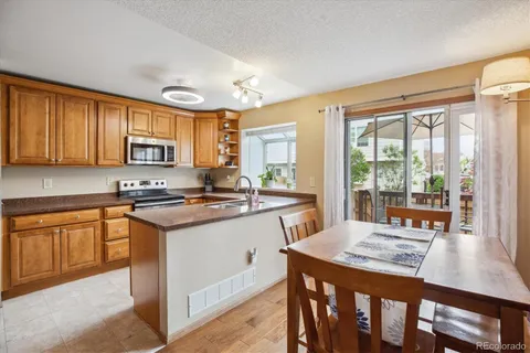 a kitchen with stainless steel appliances granite countertop a stove top oven a sink dishwasher a dining table and chairs with wooden floor