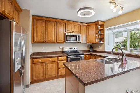 a kitchen with stainless steel appliances granite countertop a stove a sink dishwasher and a refrigerator with wooden floor