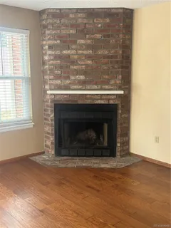 an empty room with wooden floor a fireplace and windows