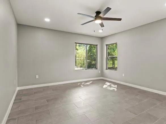 an empty room with windows and ceiling fan