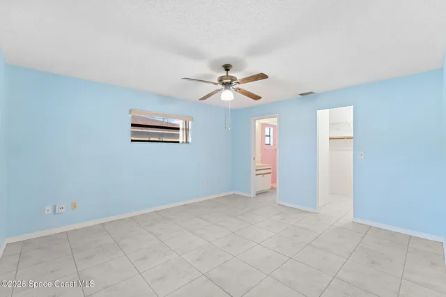 an empty room with windows and ceiling fan