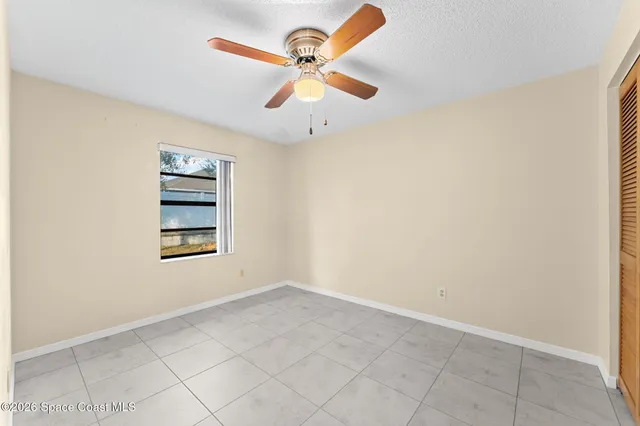 an empty room with windows and ceiling fan