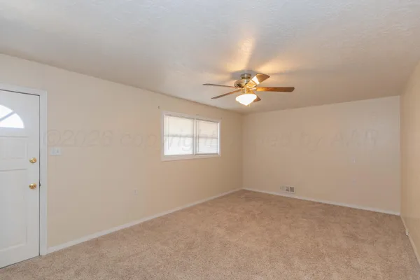 an empty room with a window and a ceiling fan
