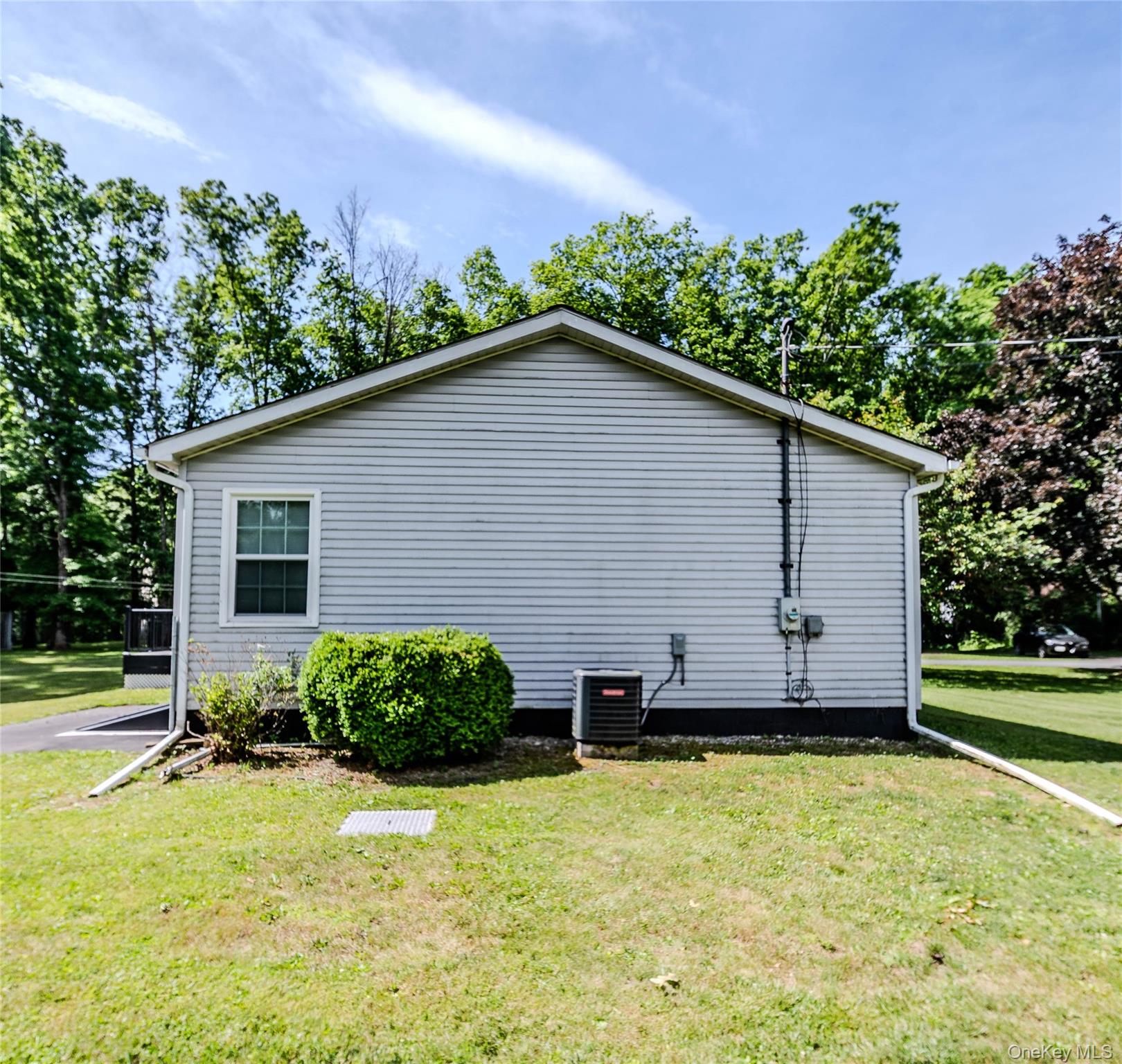 15 Van Dewark Road Middletown, NY 10941 - Photo 40 of 41 Light-toned siding exterior with a pitched roof, featuring a double-hung window with white trim, a visible HVAC unit, and a well-maintained lawn