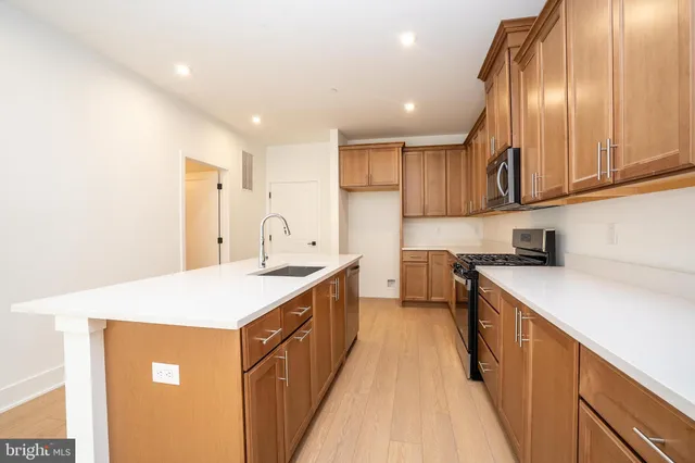 a kitchen with a sink a stove cabinets and a wooden floor