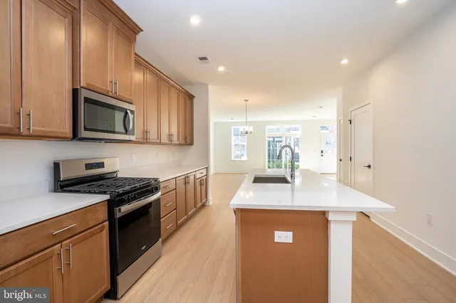 a kitchen with stainless steel appliances granite countertop a sink dishwasher stove and microwave with wooden cabinets