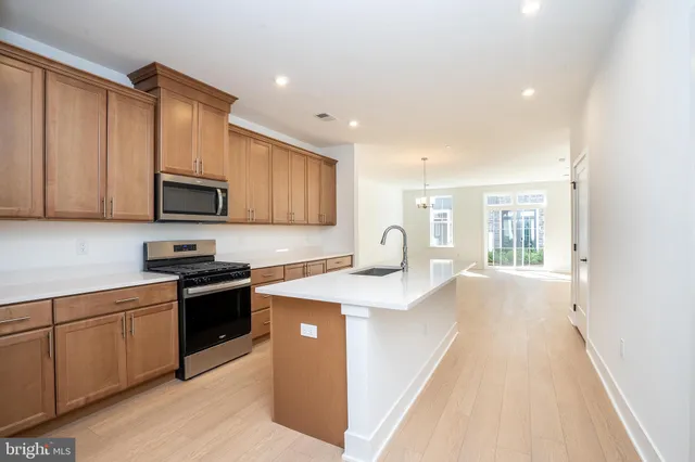 a kitchen with stainless steel appliances granite countertop a sink stove refrigerator and cabinets