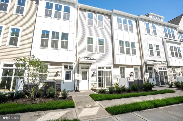 a front view of a building with a yard and plants
