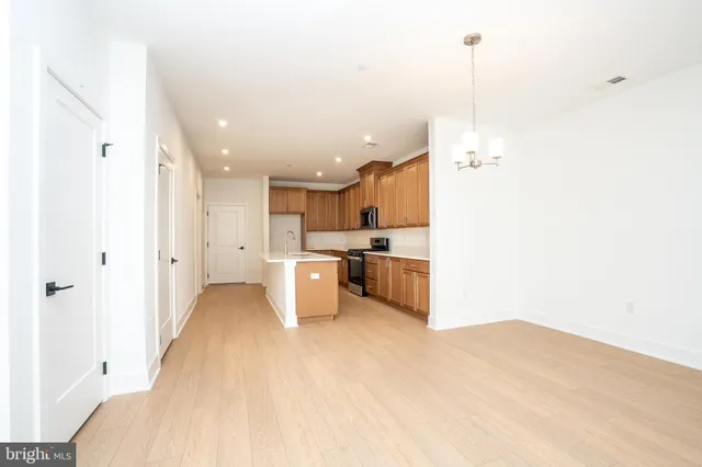 a view of kitchen and empty room with wooden floor