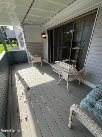 a balcony with wooden floor and outdoor seating