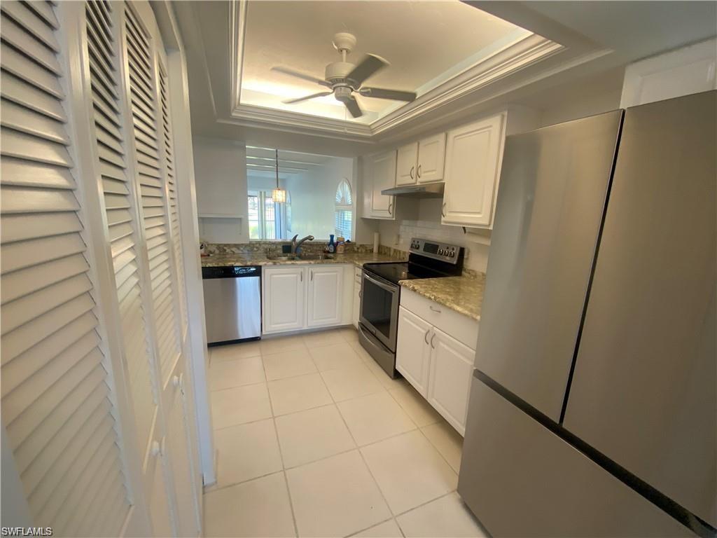 705 Augusta Boulevard, Unit 7055 Naples, FL 34113 - Photo 3 of 18 a kitchen with white cabinets and white appliances