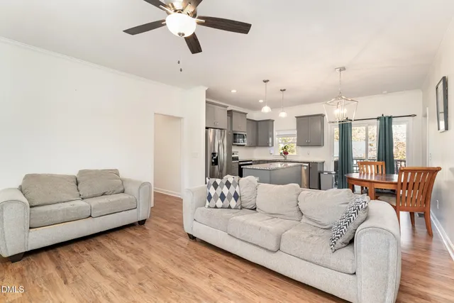 a living room with furniture kitchen view and a chandelier