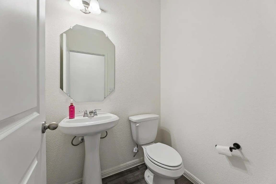 19605 Caymus Drive Pflugerville, TX 78660 - Photo 18 of 26 Half bathroom with dark wood finished floors and a textured wall