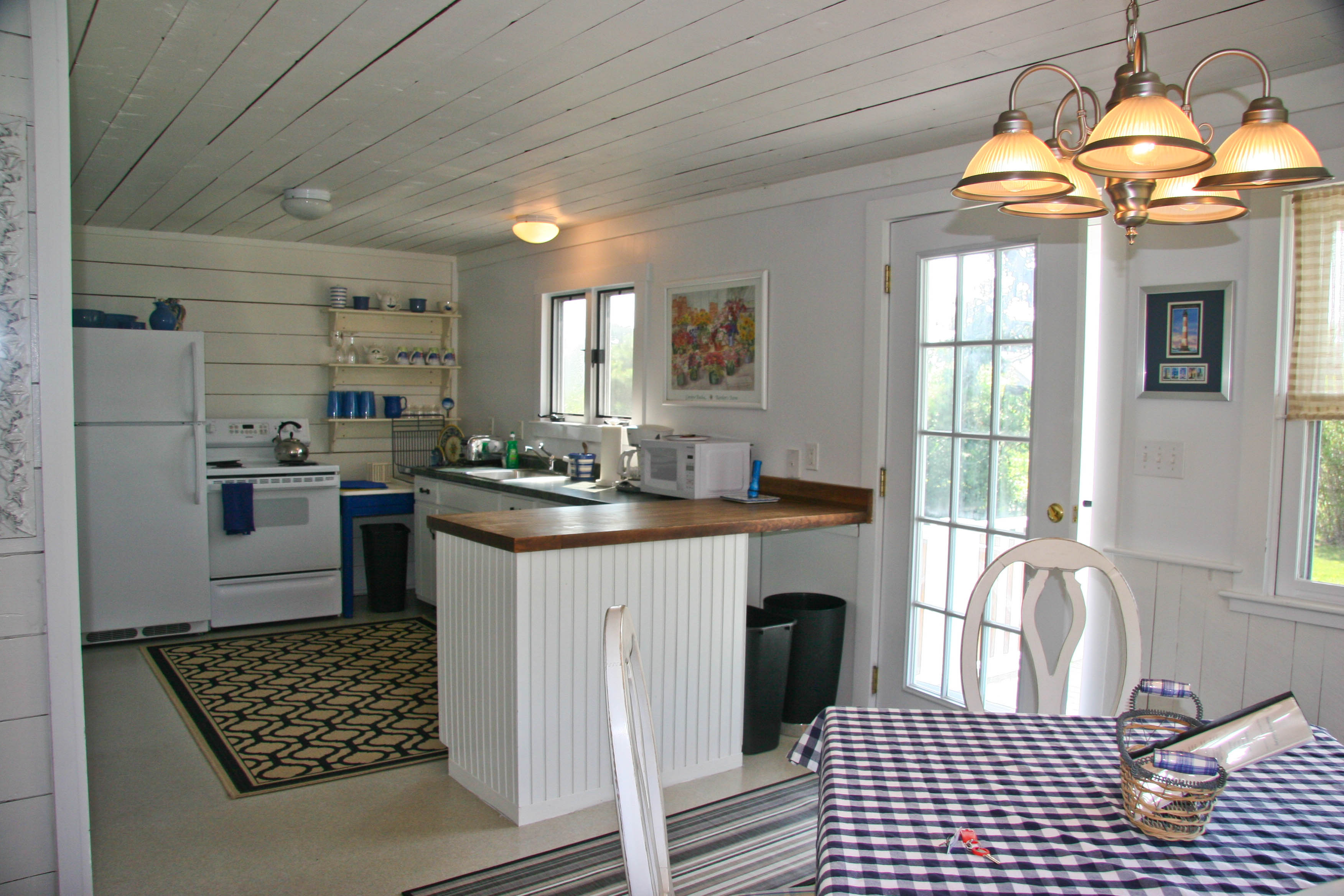 144 Surfside Road Nantucket, MA 02554 - Photo 40 of 46 a kitchen with granite countertop a stove a sink dishwasher a dining table and chairs with wooden floor