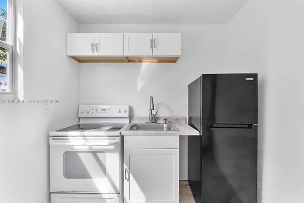 a kitchen with appliances a refrigerator and cabinets