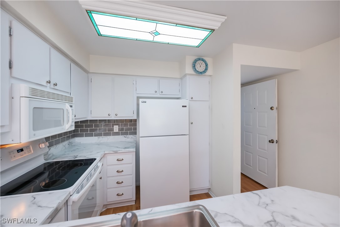 1100 Pondella Road, Unit 514 Cape Coral, FL 33909 - Photo 15 of 35 a kitchen with granite countertop a refrigerator a stove a microwave and cabinets