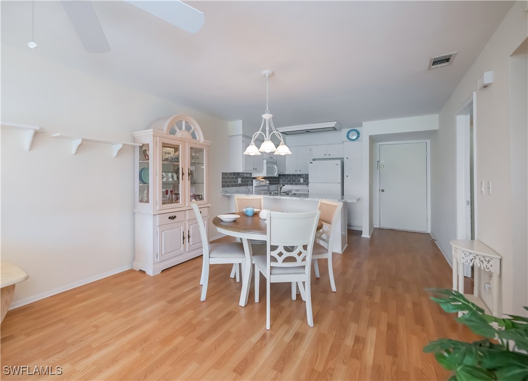 1100 Pondella Road, Unit 514 Cape Coral, FL 33909 - Photo 16 of 35 a view of a dining room with furniture a chandelier and wooden floor