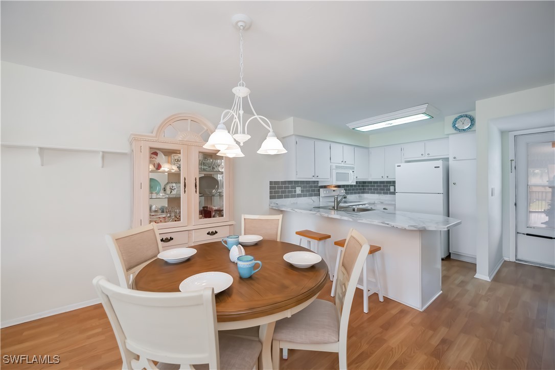 1100 Pondella Road, Unit 514 Cape Coral, FL 33909 - Photo 19 of 35 a dining room with wooden floor a chandelier a wooden table and chairs