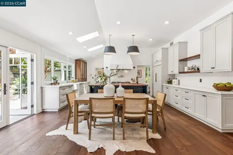 a kitchen with stainless steel appliances kitchen island granite countertop a dining table chairs and white cabinets