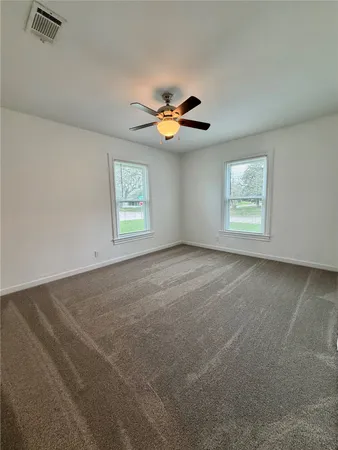 an empty room with windows and fan