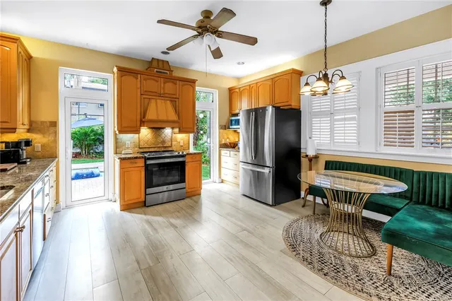 a kitchen with stainless steel appliances granite countertop a sink dishwasher a stove and a refrigerator with wooden floor