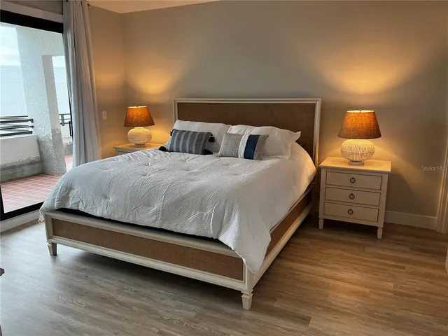 a view of an empty room with wooden floor and windows