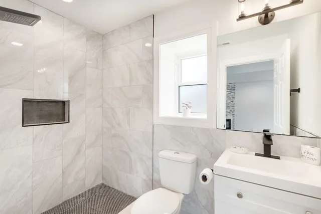 a bathroom with a toilet sink vanity and mirror
