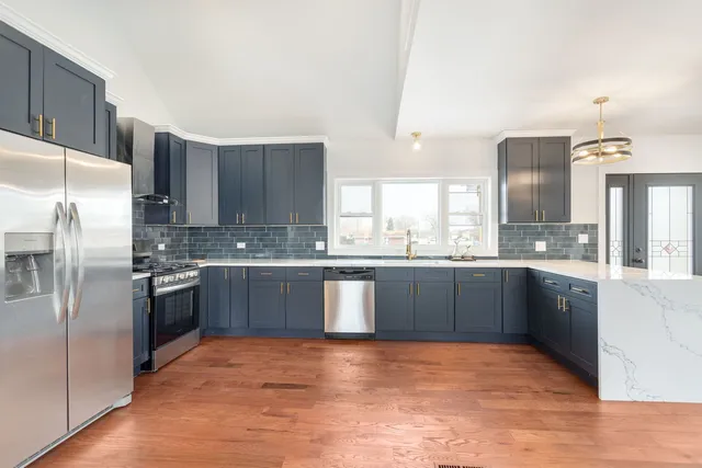 a large kitchen with stainless steel appliances granite countertop a refrigerator a sink dishwasher a stove with wooden cabinets and floor