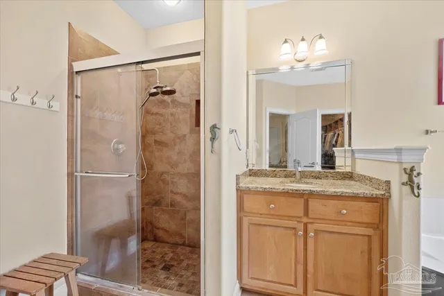a bathroom with a granite countertop shower sink vanity and mirror